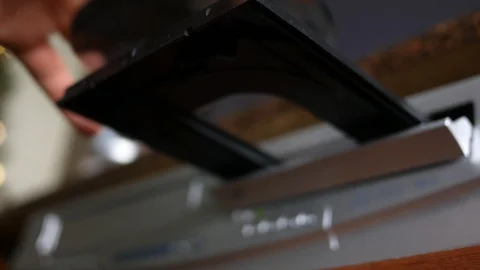 Person inserts a DVD laser disc into the DVD player and pushes it into the tray Vidéo 90104099