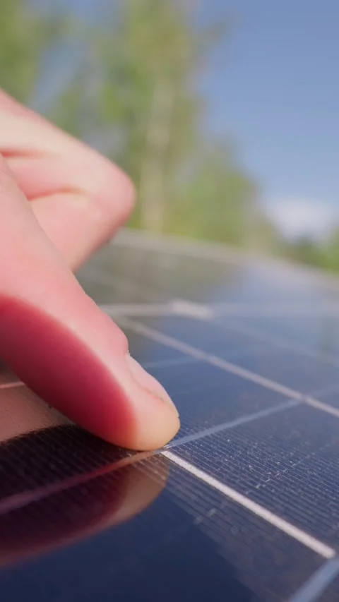 Person Inspecting Dusty Solar Panel Surface in Bright Sunlight Stockbeeldmateriaal 345160678