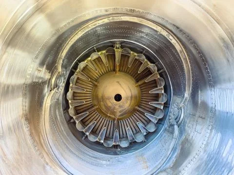 A person inspects the inside of a jet engine, focusing on the turbine blades  Stock Photos