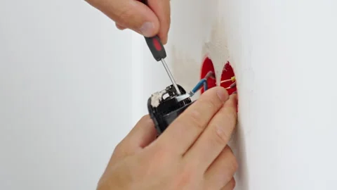 Person installing electrical outlet in wall with screwdriver Stock Footage 346002922