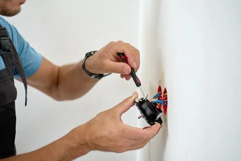 Person installing electrical outlet in wall at home Stock Photos