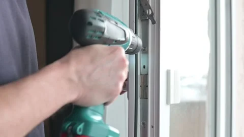 A person installs a window frame using a power drill in a home setting. 스톡 동영상 337111512