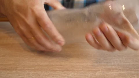 Person intensely crushing an empty plastic bottle by hand in close up on a wo Stock Footage 341194681