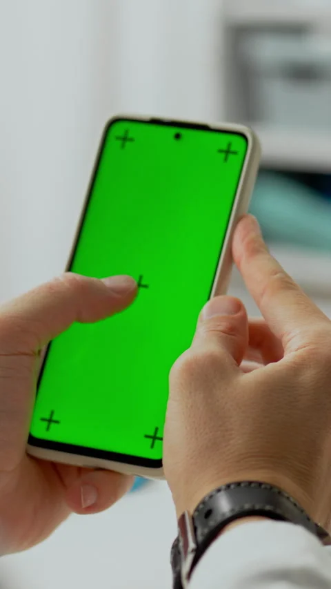 Person interacting with a smartphone displaying a bright green screen indoor Stock Footage 331672183