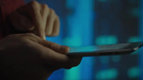 Person interacting with a tablet device in a dimly lit environment with colo Stock Footage 288621399