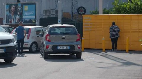 A person interacts with a parcel locker while cars are parked nearby, illus.. Stock Photos