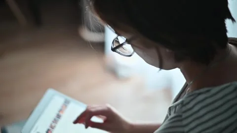 A person interacts with a tablet while wearing glasses and a mask. The setting Stockbeeldmateriaal 336778610