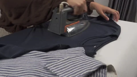 Person ironing clothes on table Stock Footage 276399115