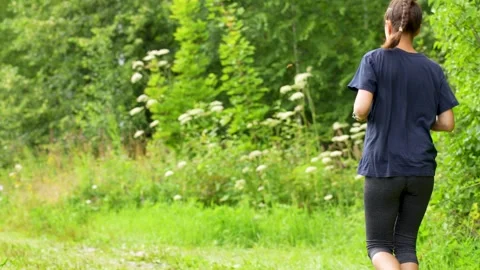 Person Jogging on Grassy Forest Path Stock Footage 314006150
