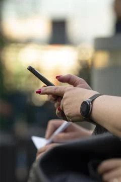 Person jotting down thoughts with tech gadgets by sunset coast Stock Photos