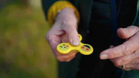 A person is joyfully playing with a vibrant and colorful fidget spinner while Stock Footage 308335586