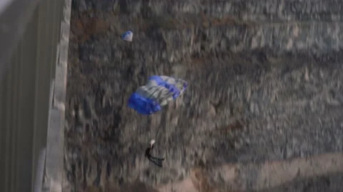 Person jumping off of a bridge to base jump with their parachute, then fly Stock Footage 195087001