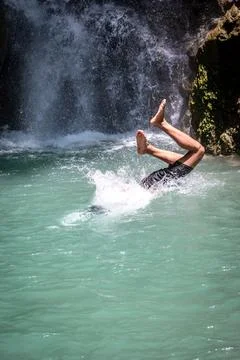 Person jumping into a refreshing waterfall pool with powerful splash. Foto stock