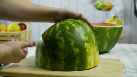 Person with knife trying to cut large watermelon half down the middle - closeup Stock Footage 341272817