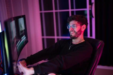 Person laughing while gaming at a computer setup in a dimly lit room during.. Foto stock