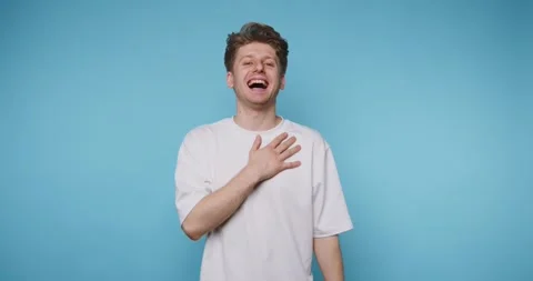 Person laughs and smiles while standing in front of a blue background showi.. Video stock 331990851