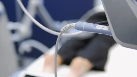 A person is laying on a bed with a machine attached to their leg Stock Footage 297653066