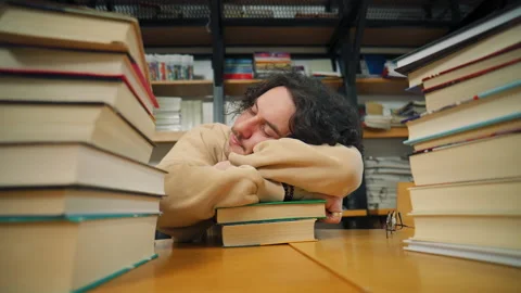 A person is leaning on books at a library, surrounded by stacks of books and she Video stock 337139030