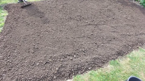 Person leveling soil with a garden rake for a new flowerbed Stock Footage 334850856