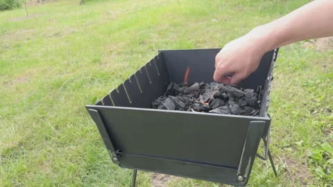 Person lighting charcoal firewood in barbecue grill Stock Footage 338408557