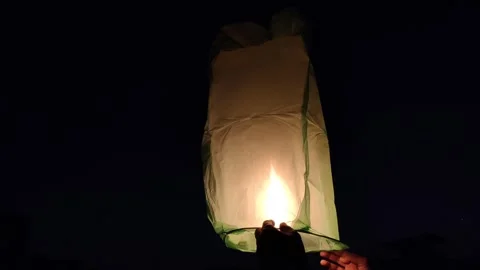 Person lighting up a paper lantern Stock Footage 299711931
