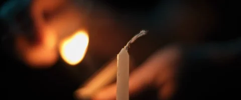Person lighting up a white candle in a dark room, slow motion Stock Footage 124664008
