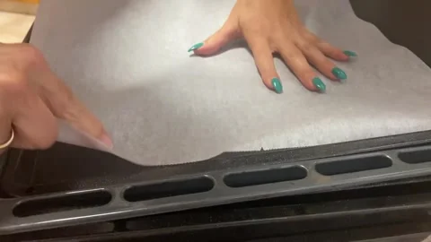 Person lining oven tray with parchment paper for baking Stock Footage 317982133