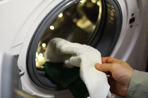 Person Loading Clothes into a Modern Front-Loading Washing Machine for Laundr Stock Photos
