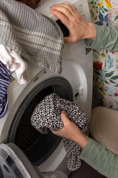 A person is loading freshly sorted laundry into a washing machine. The settin Stock Photos