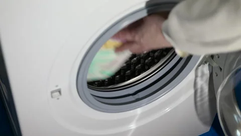 Person loading laundry into a washing machine Stock Footage 345482542