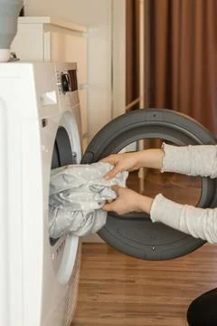 Person loading laundry into washing machine in a modern home setting during.. Foto stock