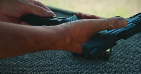 Person loading semi-automatic pistol with ammunition during shooting range Stock Footage 312219619