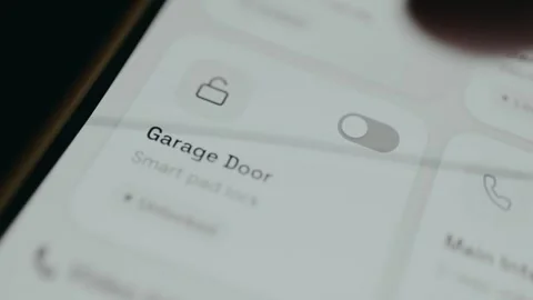 Person locks the Garage Door using a smart home security application on mobile Stock Footage 333379594