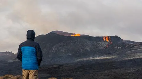 Person looking at an Active Volcano with exploding red Lava in Iceland Stock Photos