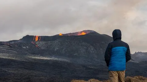 Person looking at an Active Volcano with exploding red Lava in Iceland Stockfoto's