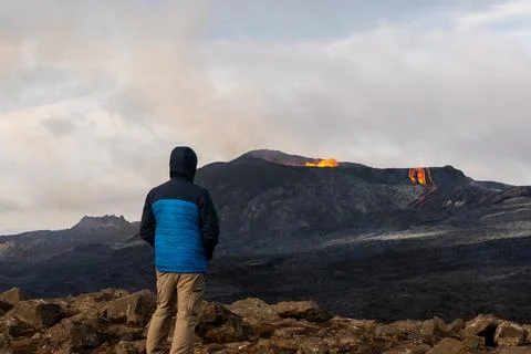 Person looking at an Active Volcano with exploding red Lava in Iceland Stock Photos