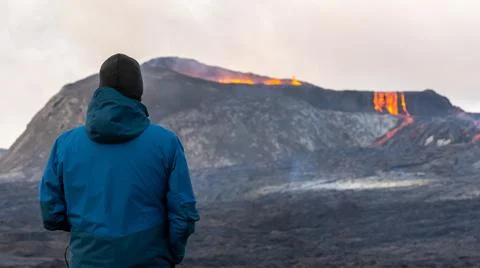Person looking at an Active Volcano with exploding red Lava in Iceland Stock Photos