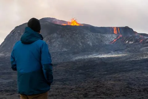 Person looking at an Active Volcano with exploding red Lava in Iceland Stock Photos