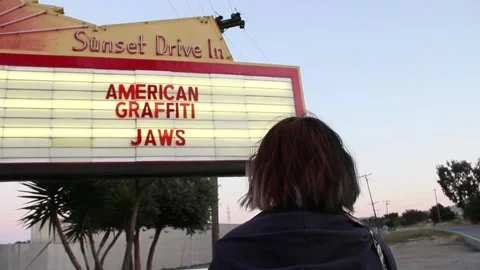 Person looking at drive in marquee of Jaws and American Graffiti Stock Footage 150381439