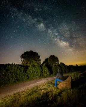 A person looking at the milky way sitting on a rock Stock Photos