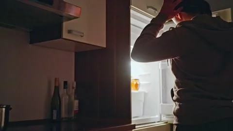 A person is looking into an open refrigerator during the night, seeking Stock Footage 309245219