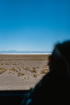 A person is looking out the window of a car, looking at a desert landscape Stock Photos