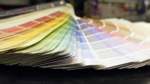 A person looking through an array of colorful paint swatches on a black sur.. Stock Footage 332745605