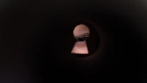 Person looking through keyhole observing with suspicious eye 스톡 동영상 285770982