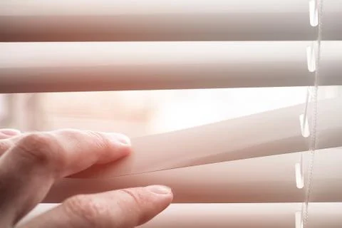 Person looking through the window shutters. Stock Photos