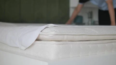 Person making bed by smoothing white sheet on mattress, close up slow motion. Stock Footage 333156049