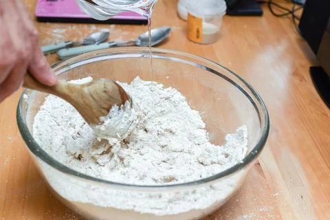 Person making bread in home kitchen adding ingredients to make the dough Stock Photos