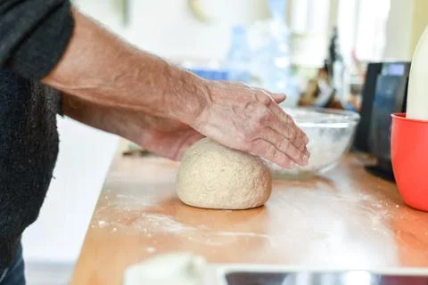Person making bread in a home kitchen adding ingredients to make the dough an Stock Photos