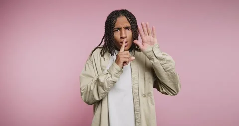 Person making a gesture to keep quiet in front of a pink background while d.. Vídeo Stock 326788020