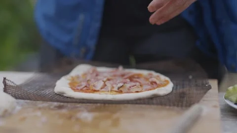 A person is making a pizza with bacon on it Video stock 297842744